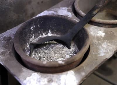Babbitt pots with a ladle stirring molten metal